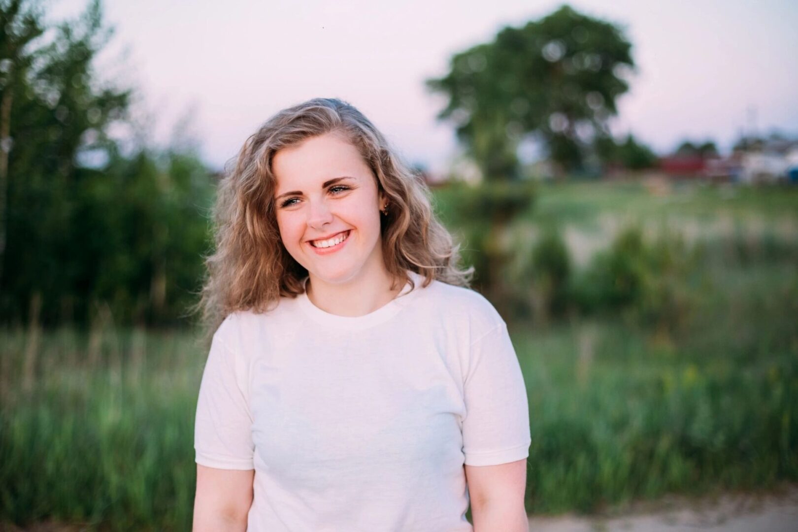 A woman in white shirt standing on grass field.