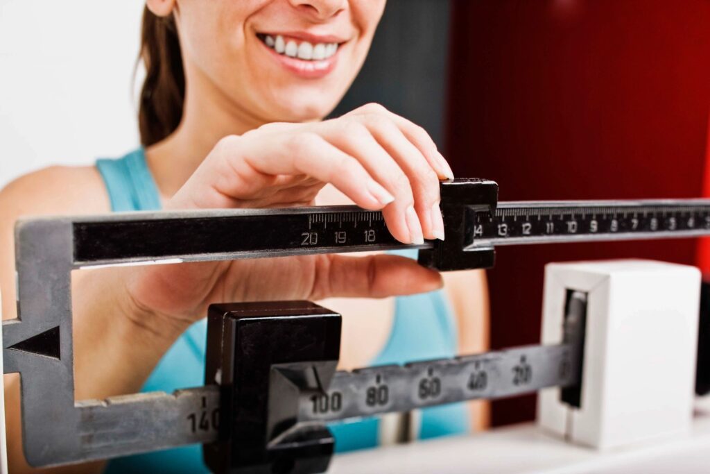 A woman is smiling while standing on a scale.