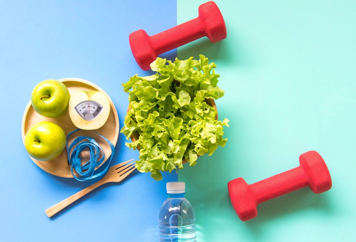 A bottle of water, lettuce and apples are on the table.