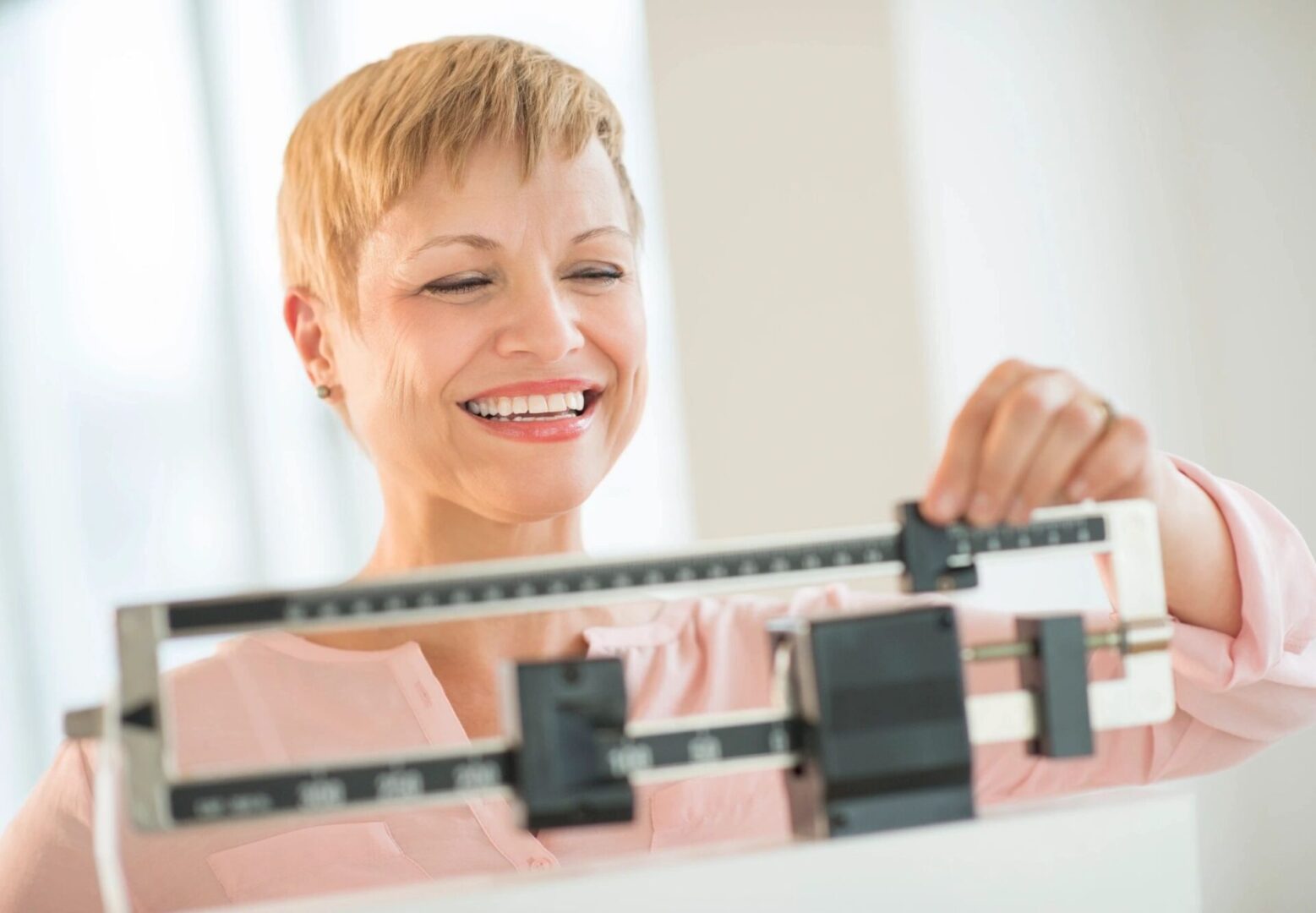 A woman is smiling while standing on a scale.