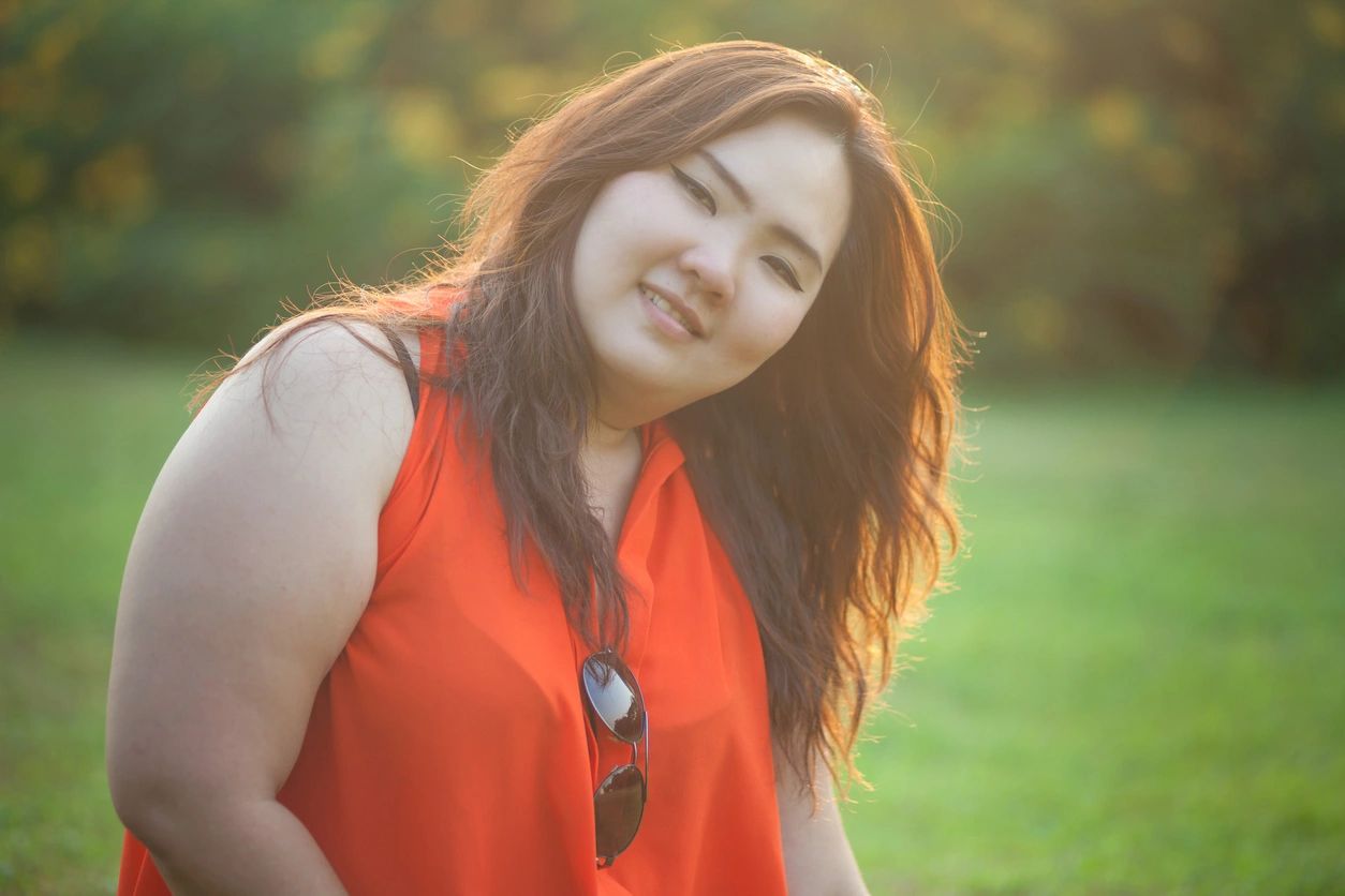 A woman in an orange top standing outside.