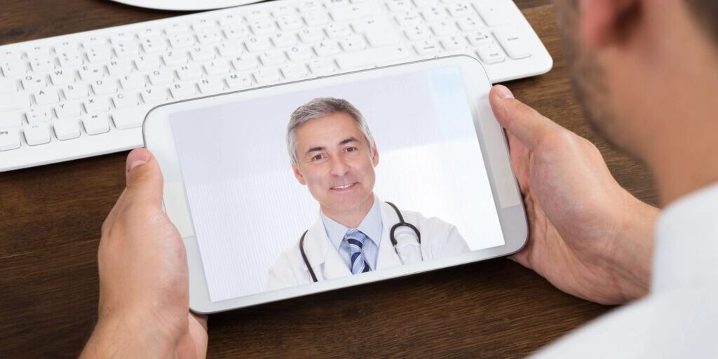 A person holding up a tablet with a picture of a doctor on it.